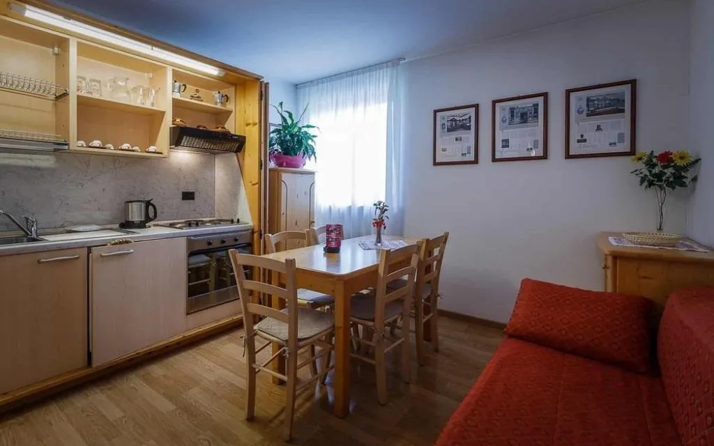Appartamento con angolo cottura, tavolo da pranzo e divano rosso