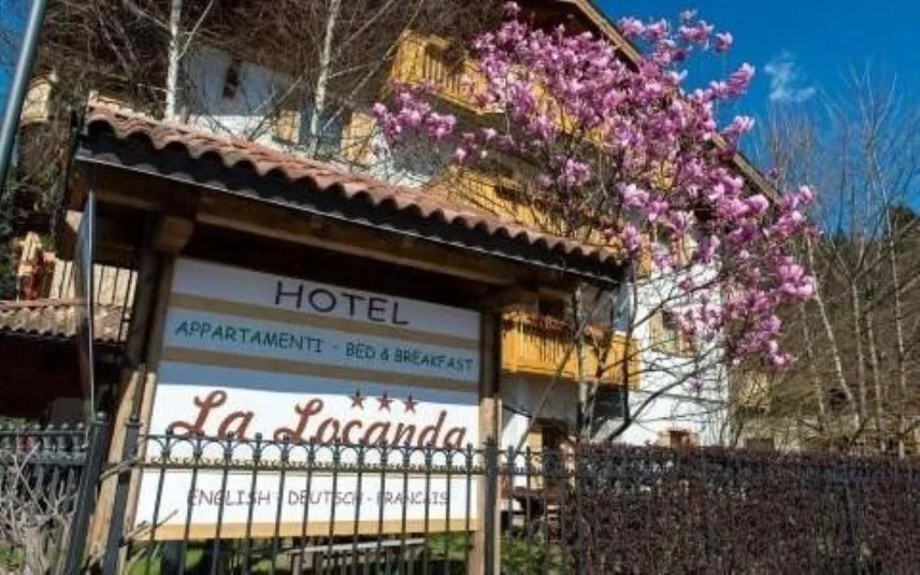 Insegna dell'hotel La Locanda con magnolia in fiore e cielo azzurro