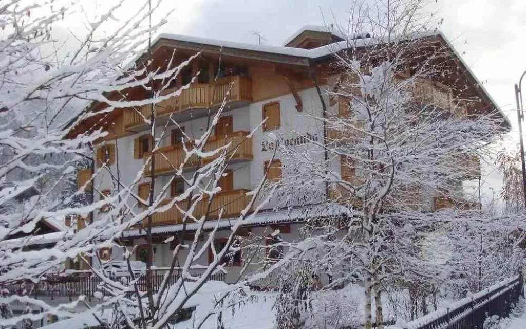 Hotel La Locanda innevato visto tra rami di alberi coperti di neve