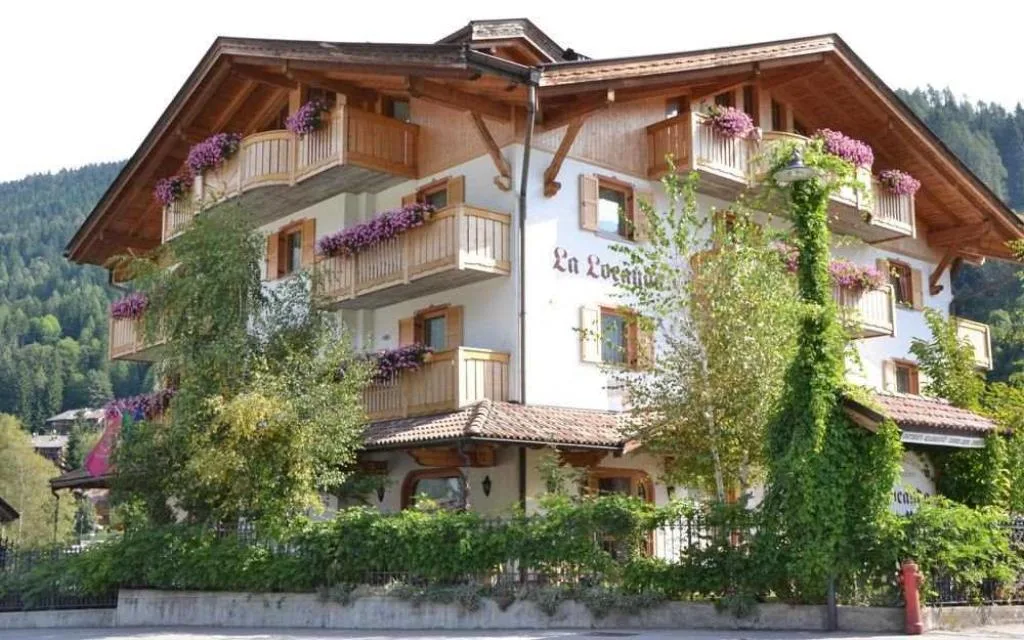 Hotel La Locanda in stile alpino con balconi fioriti e vegetazione rampicante