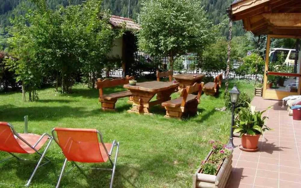 Giardino con sdraio arancioni, tavoli e panche in legno vicino alla terrazza