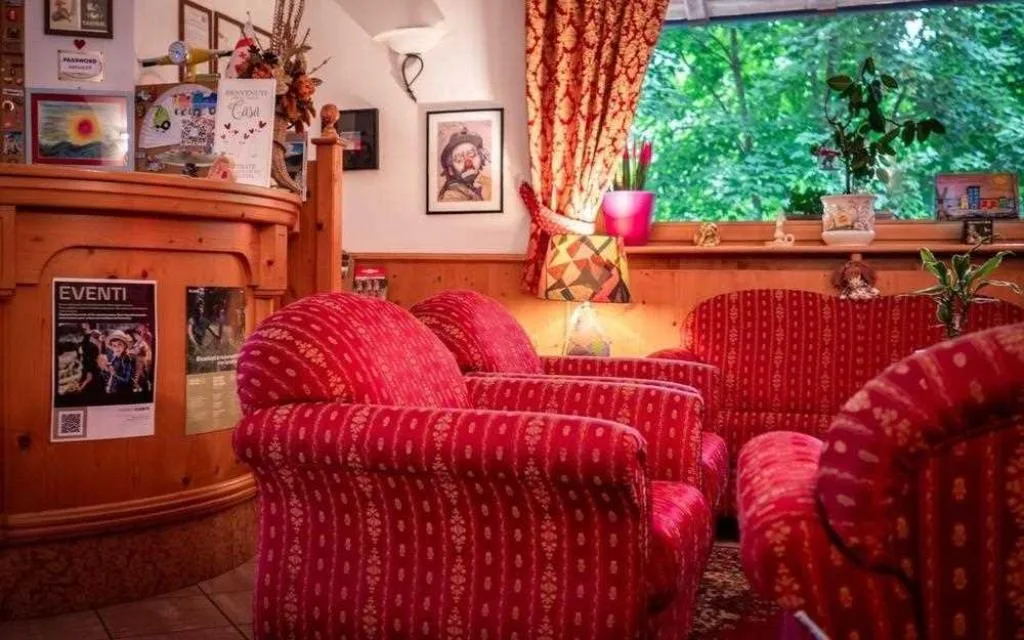 Angolo salotto della reception con poltrone rosse e finestra affacciata sul verde
