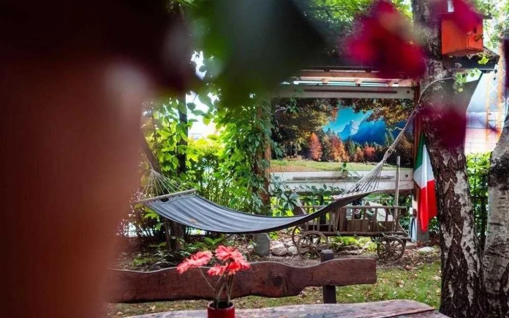 Amaca in giardino tra alberi e fiori con bandiera italiana