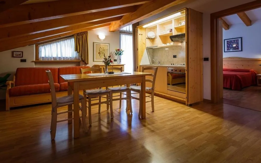 Appartamento mansardato con travi in legno, tavolo, divano e cucina
