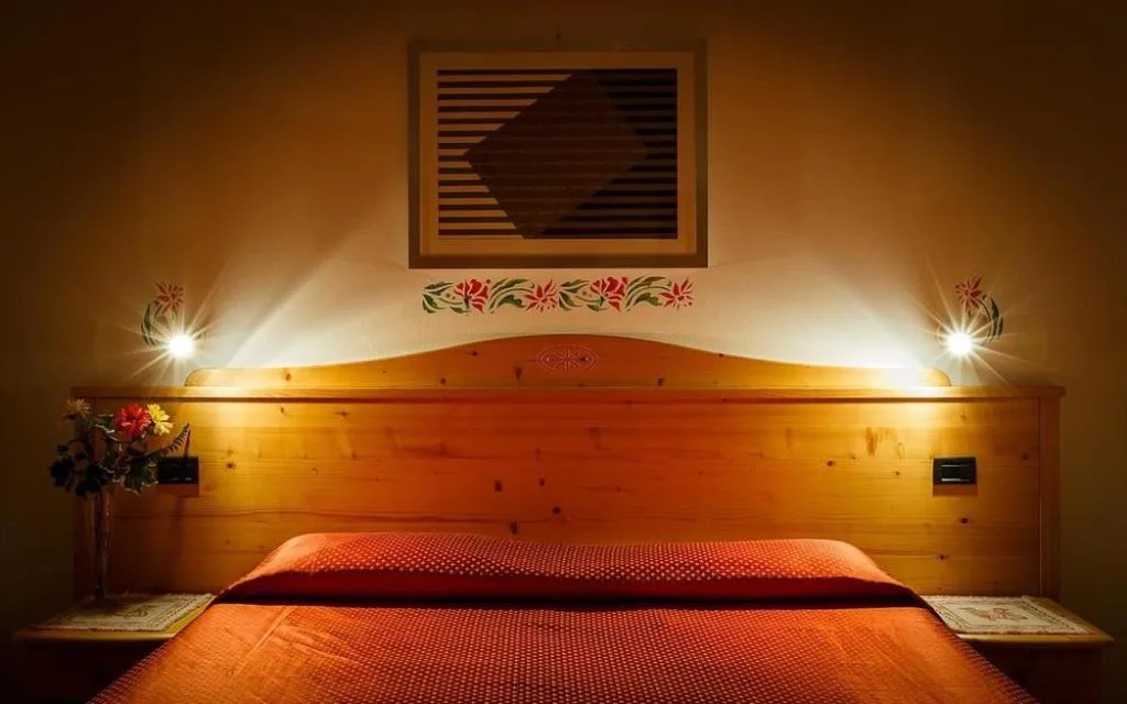 Testata del letto in legno con illuminazione soffusa e decorazioni floreali alla parete