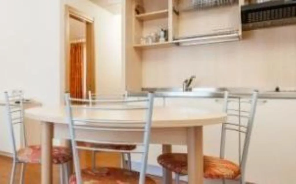 Angolo cottura dell'appartamento con tavolo rotondo, sedie e piano cucina