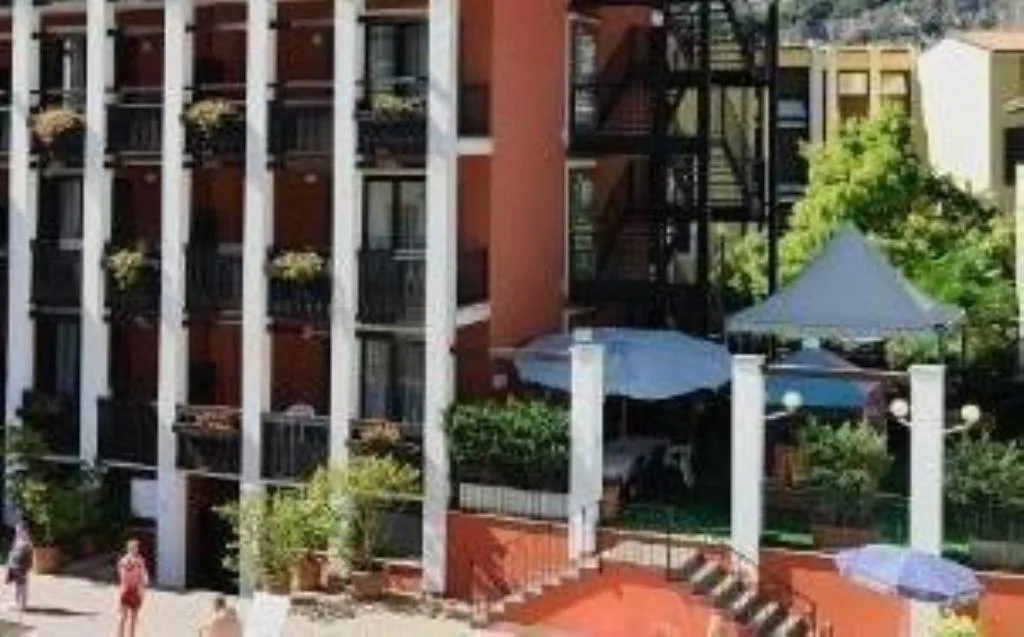 Dettaglio dell'esterno dell'hotel con balconi fioriti, ombrelloni e giardino