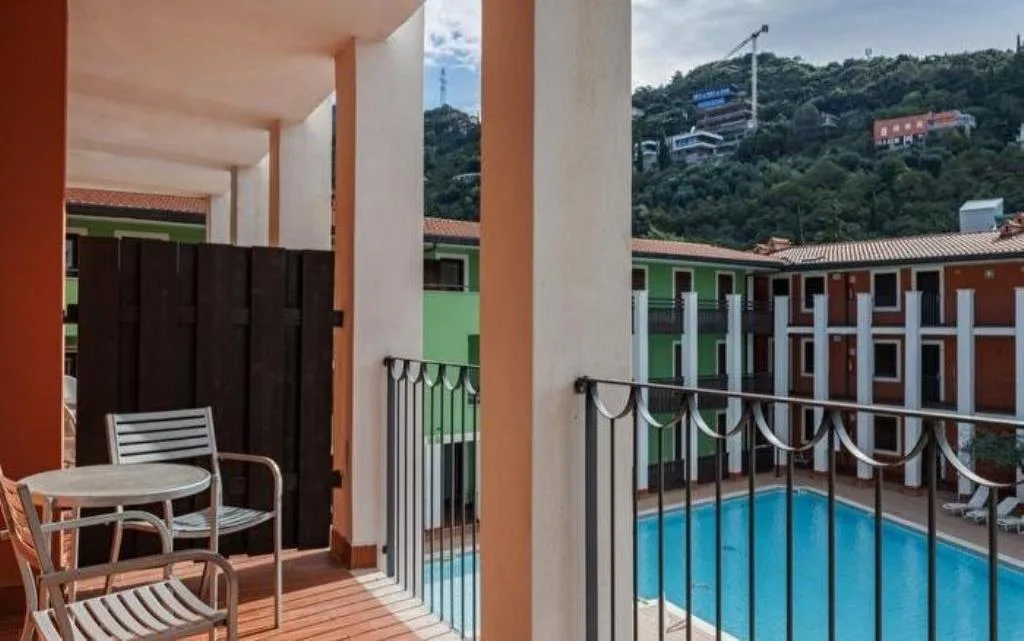 Balcone della camera con tavolino, sedia e vista sulla piscina e le colline
