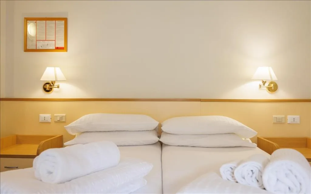 Camera con letto matrimoniale, applique dorate e asciugamani arrotolati
