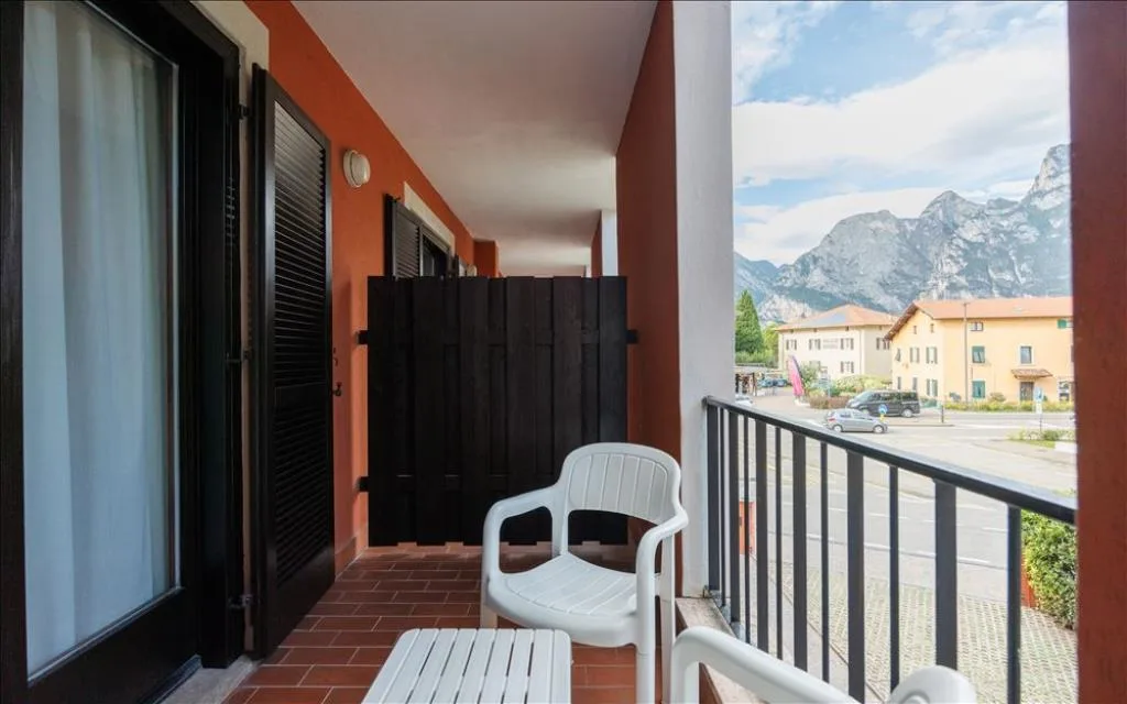 Balcone della camera con sedie bianche e vista sulle montagne e la strada