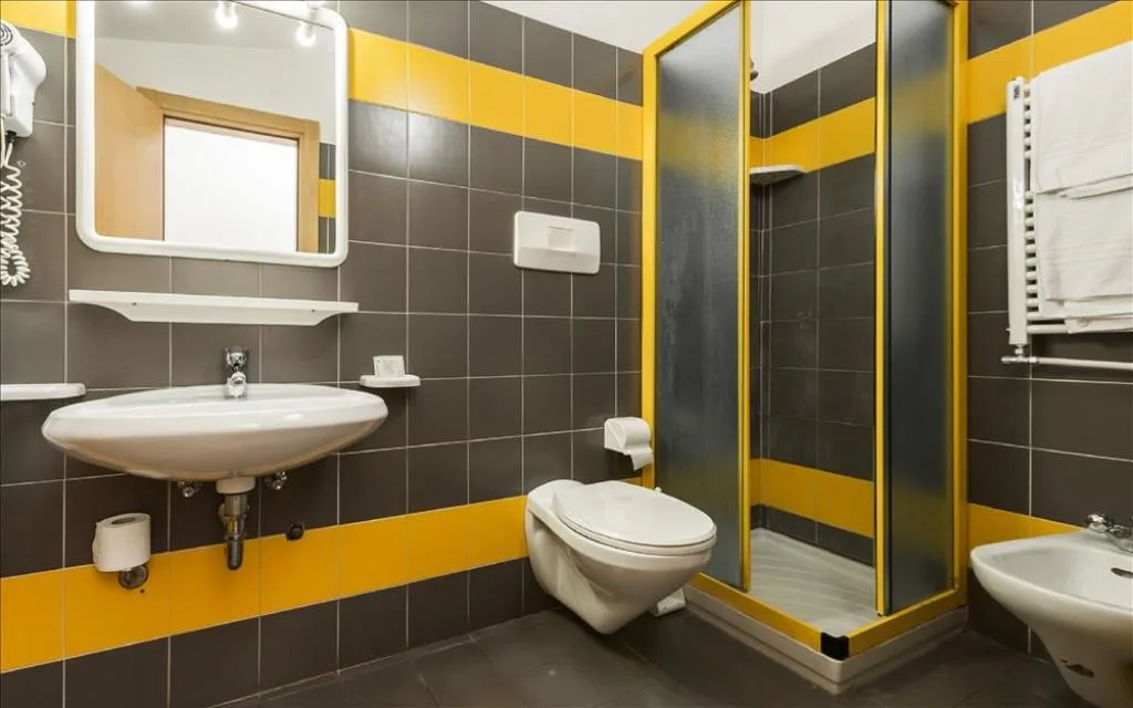 Bagno moderno con piastrelle grigie e gialle, doccia, wc e bidet