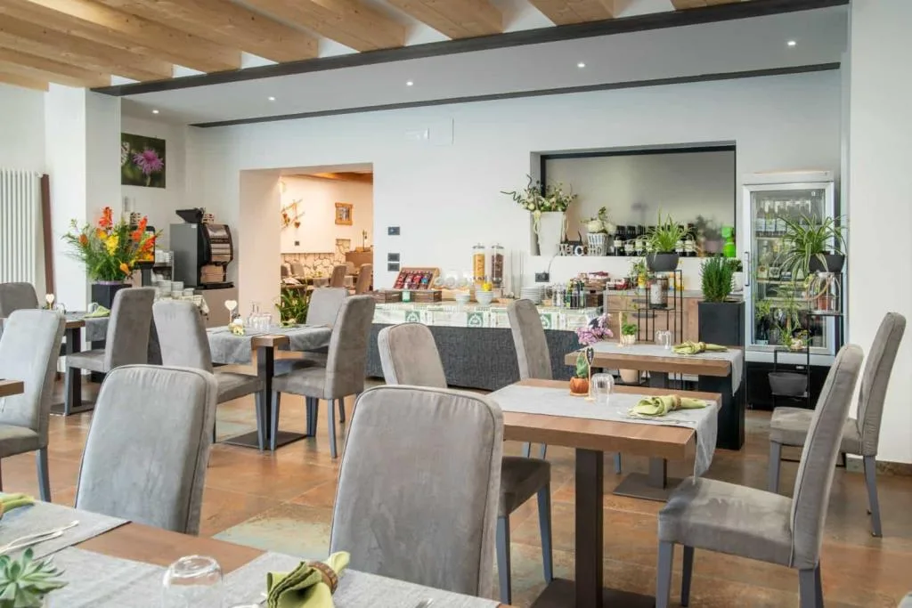 Zona ristorante e buffet moderna con tavoli, piante verdi e frigo bevande