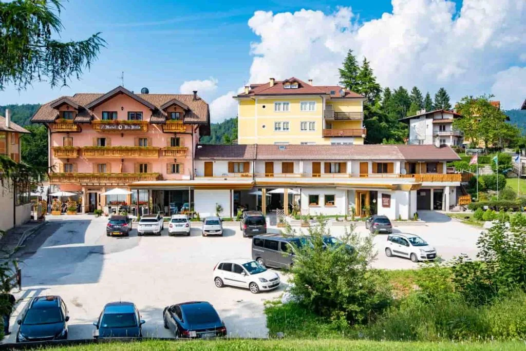 Veduta dell'hotel con ampio parcheggio e giardino verde in giornata soleggiata