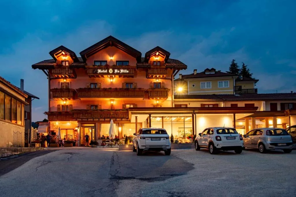 Hotel Da Villa illuminato al crepuscolo con facciata rosa e parcheggio