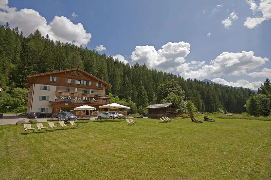 Vista estiva dell'hotel La Molinella con ampio prato verde, lettini e ombrelloni