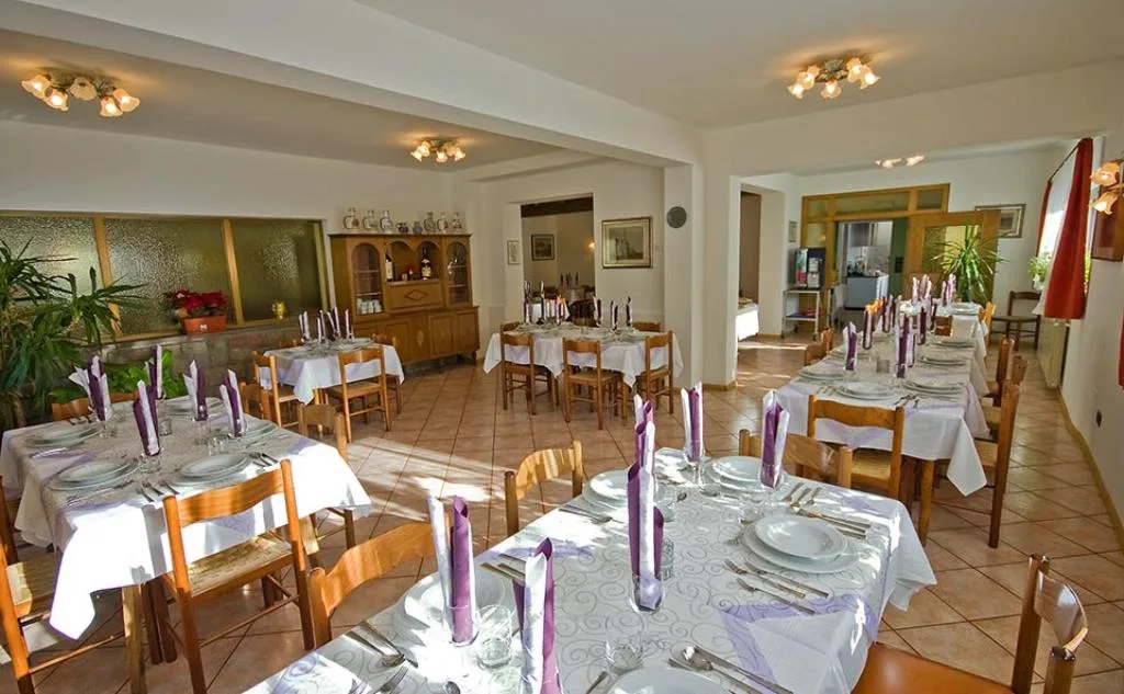 Sala ristorante con tavoli apparecchiati, tovaglie bianche e tovaglioli viola