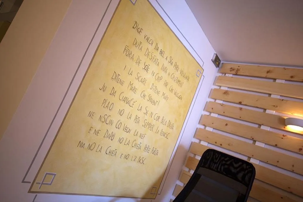 Dettaglio di parete della zona relax con poesia in lingua ladina e rivestimento in legno