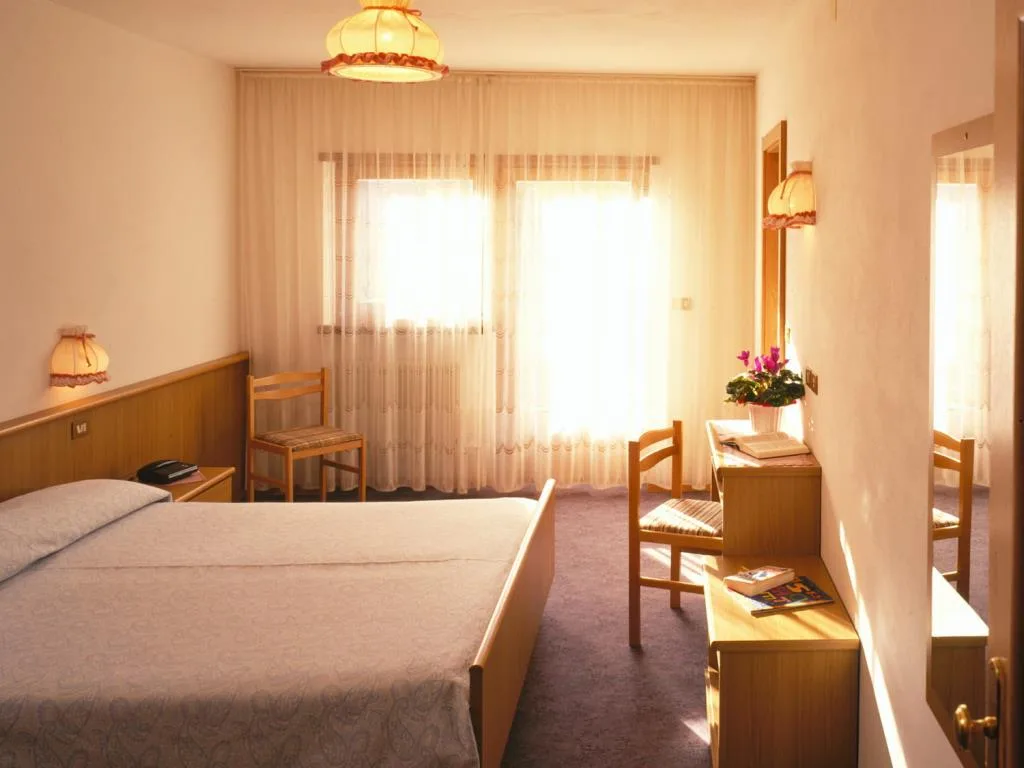 Camera matrimoniale con letto, scrivania e ampia finestra luminosa
