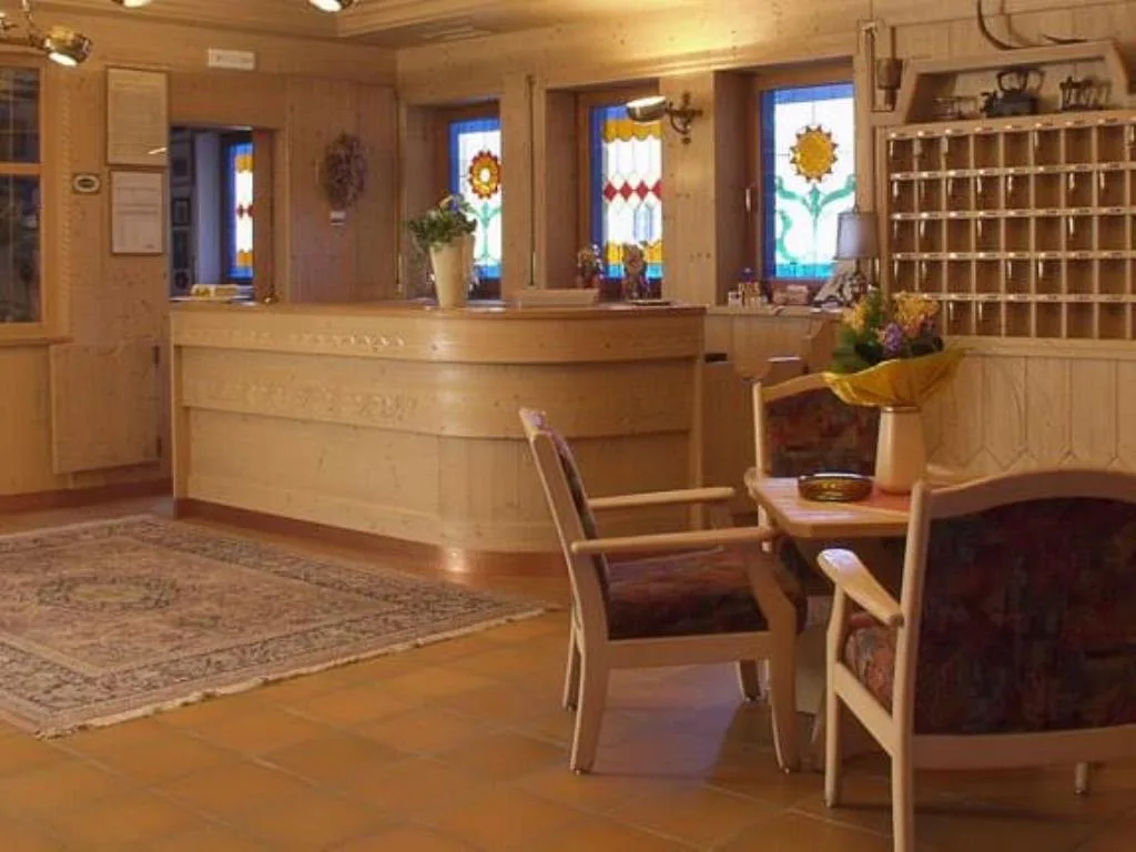 Reception dell'hotel con bancone in legno chiaro e vetrate decorate