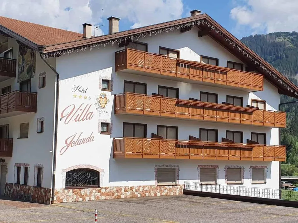 Vista laterale dell'hotel con balconi in legno e fioriere sotto cielo azzurro
