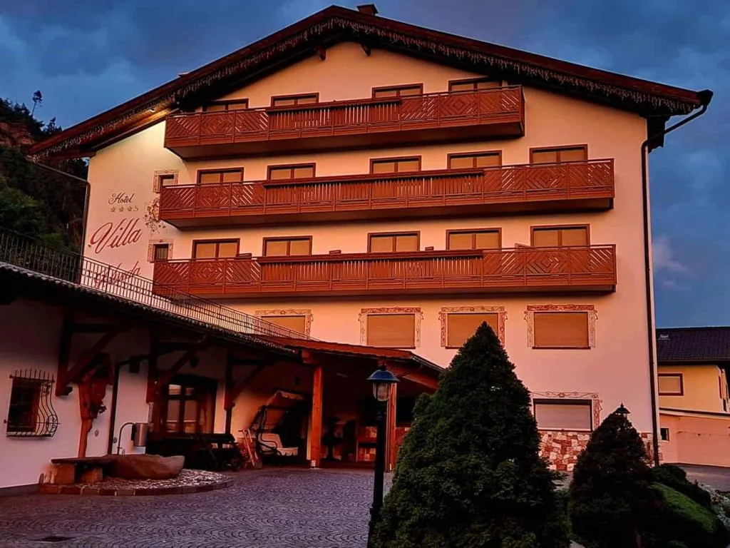 Facciata dell'hotel al crepuscolo con balconi illuminati e ingresso coperto