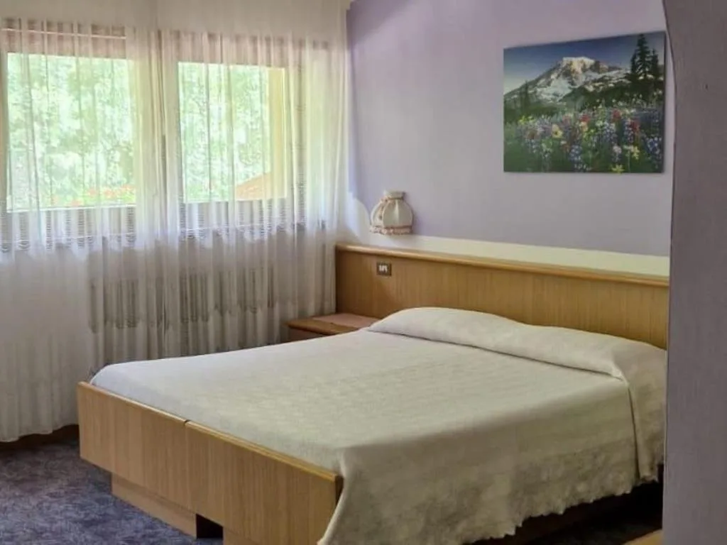 Camera doppia con letto matrimoniale e quadro di paesaggio floreale alla parete