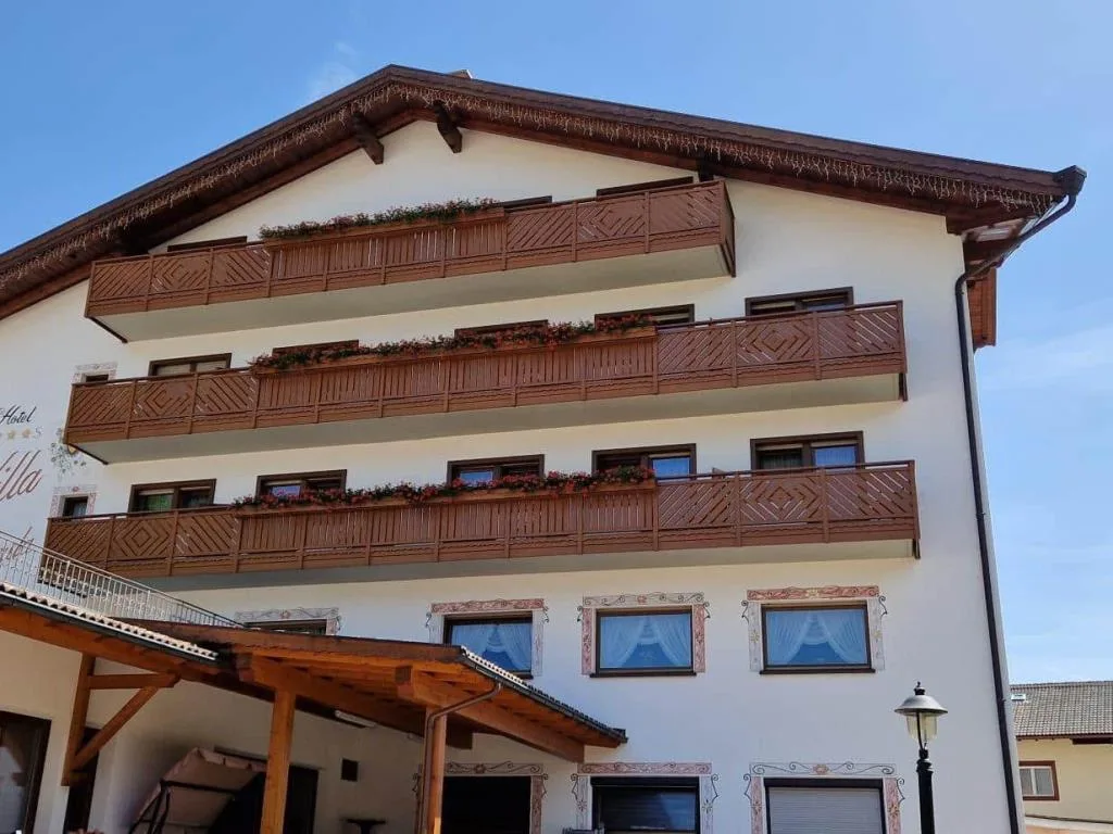 Dettaglio della facciata con balconi in legno e fioriere sotto cielo sereno