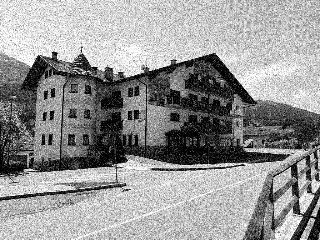 Veduta esterna in bianco e nero dell'hotel con torretta e strada antistante