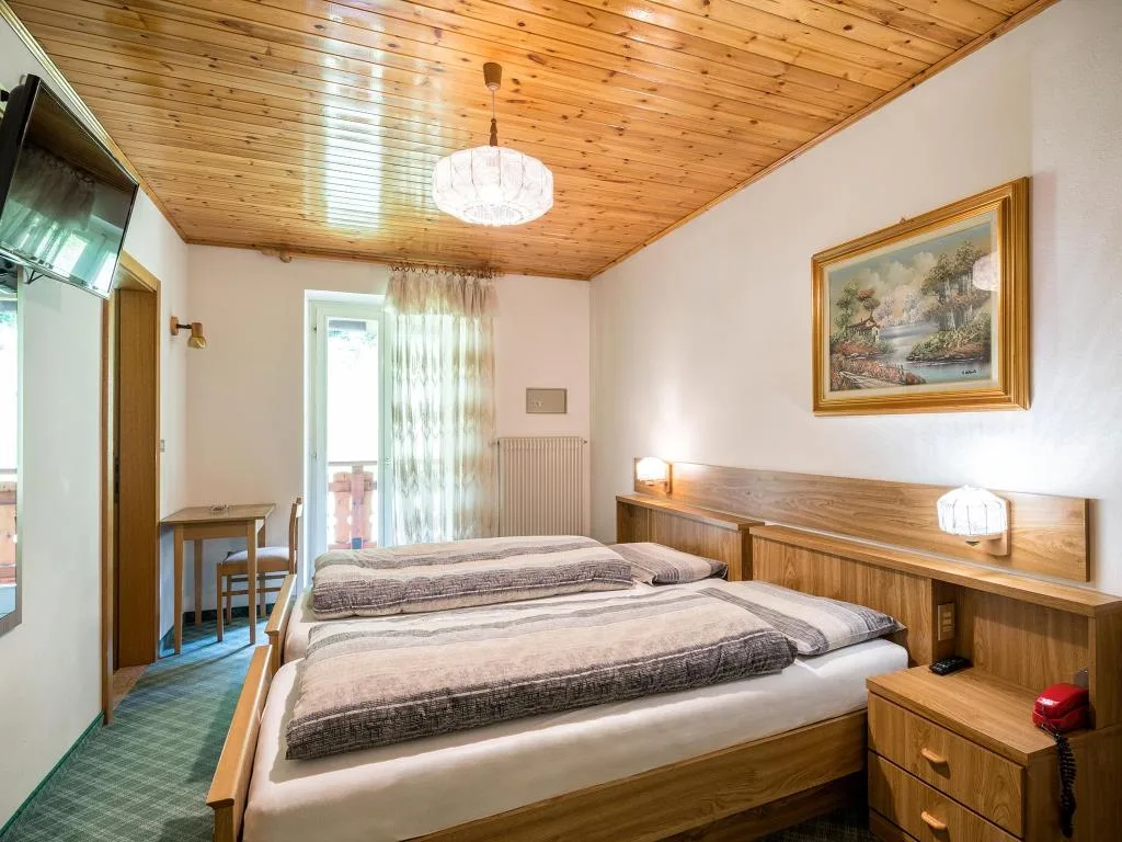 Camera matrimoniale con soffitto in legno, TV a parete e quadro decorativo
