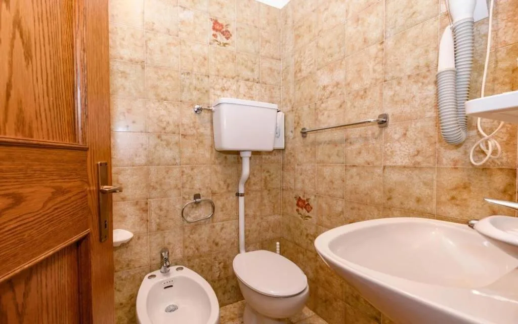 Bagno con WC, bidet, lavabo e piastrelle beige