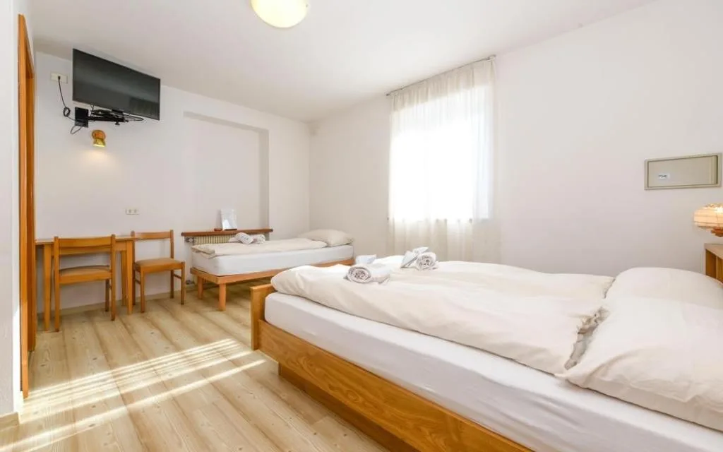 Camera luminosa con letto matrimoniale e letto singolo, pavimento in legno chiaro