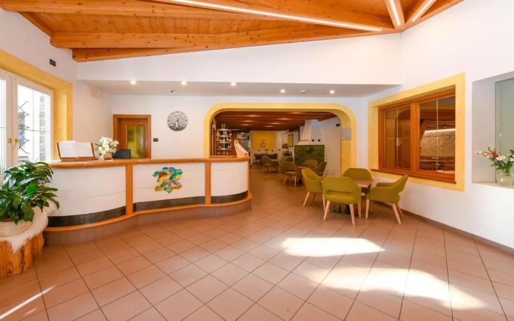 Hall dell'hotel con reception in legno e zona lounge con poltrone verdi