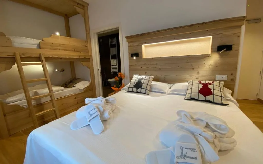 Camera in stile alpino con letto a castello in legno, letto matrimoniale con accappatoi e ciabatte