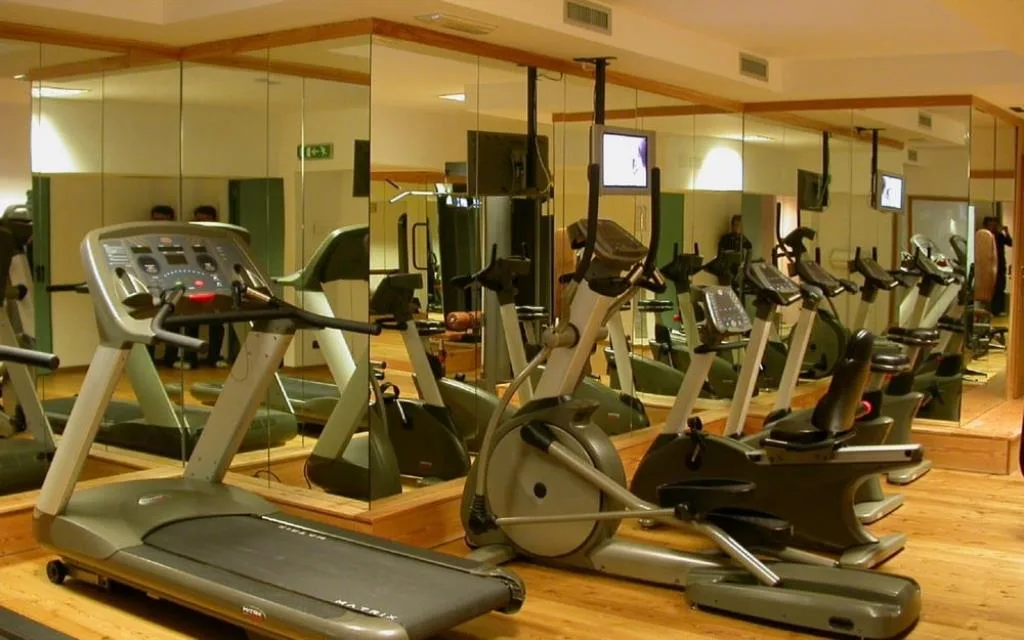Palestra attrezzata con tapis roulant, cyclette ed ellittica davanti a pareti a specchio