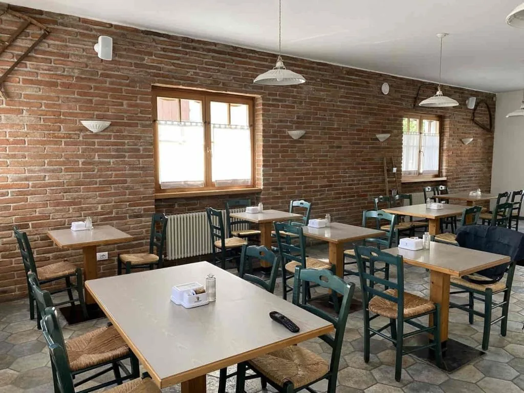 Sala ristorante con pareti in mattoni, tavoli e sedie in legno verdi