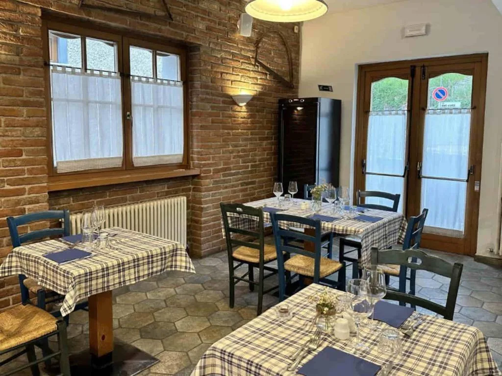 Sala da pranzo con tavoli apparecchiati con tovaglie a quadri e pareti in mattoni
