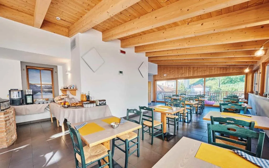 Sala colazione luminosa con soffitto in legno e buffet