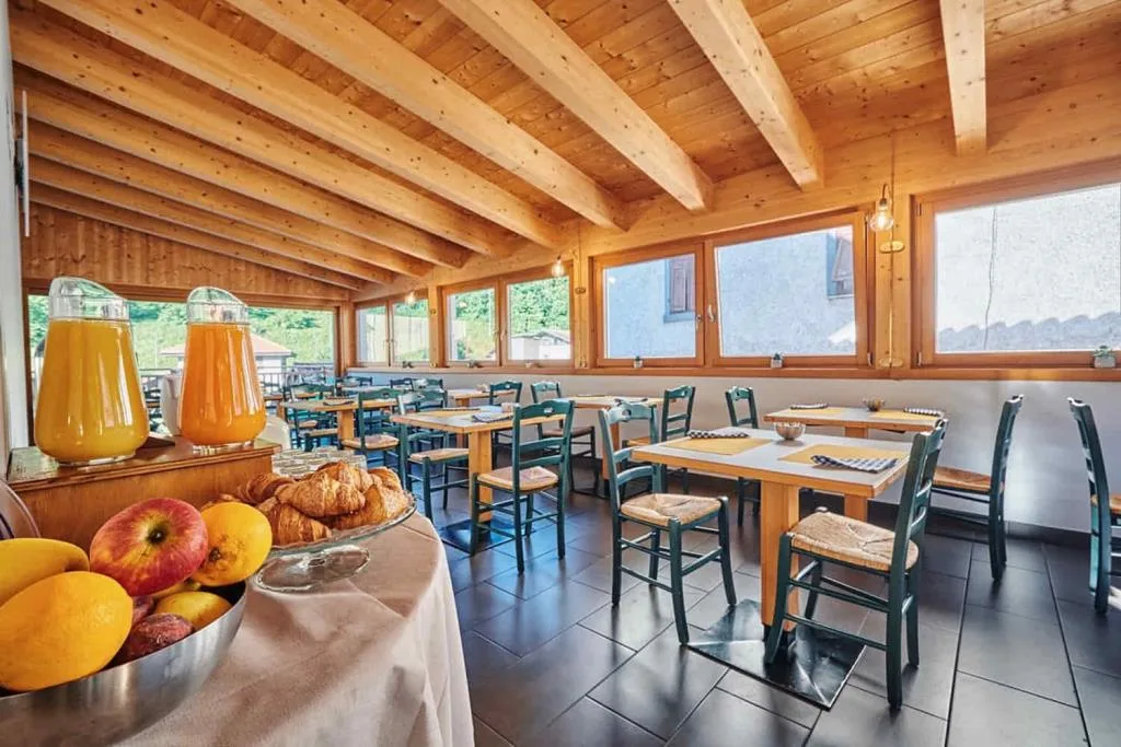 Sala colazione con soffitto in travi di legno, tavoli e succhi di frutta al buffet