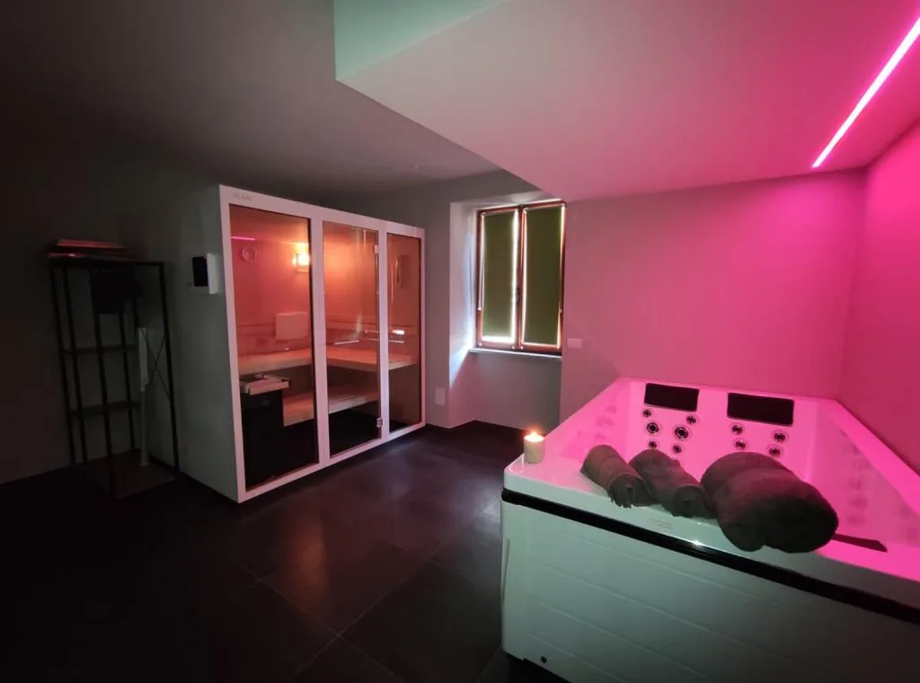 Zona spa con vasca idromassaggio e sauna illuminata da luci rosa