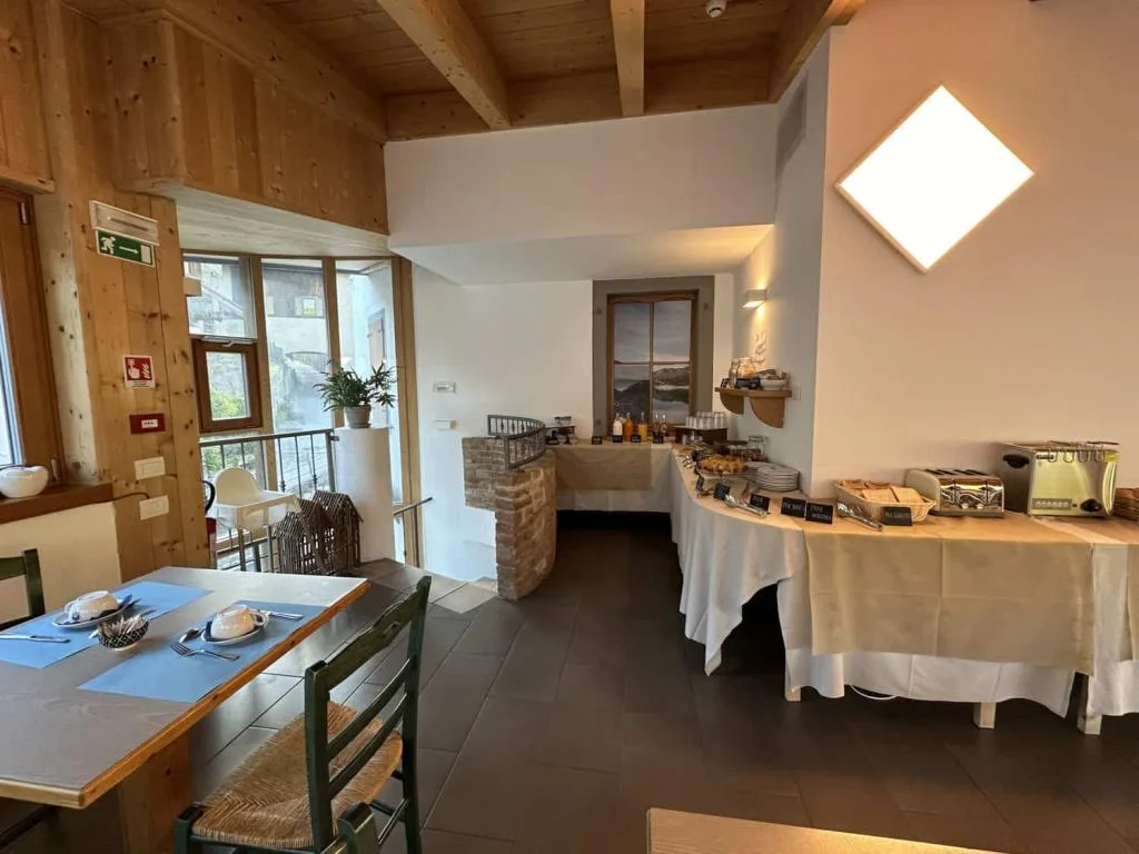Sala colazione con soffitto in legno e buffet con dolci e bevande