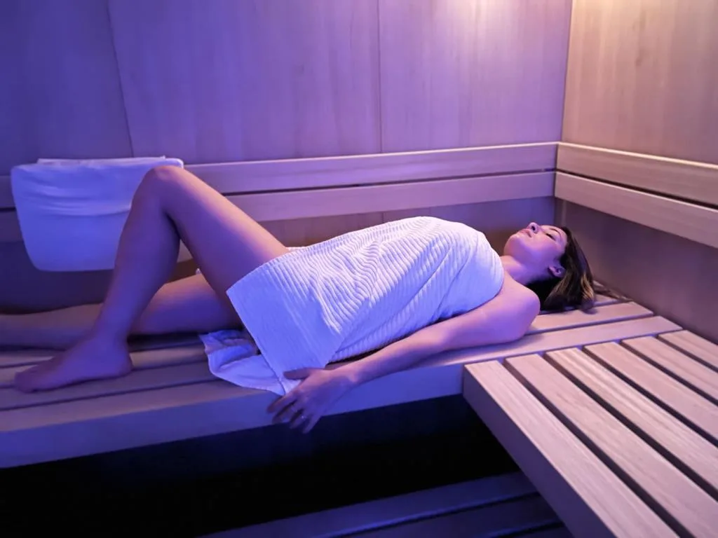 Donna rilassata nella sauna avvolta in un asciugamano con luce viola