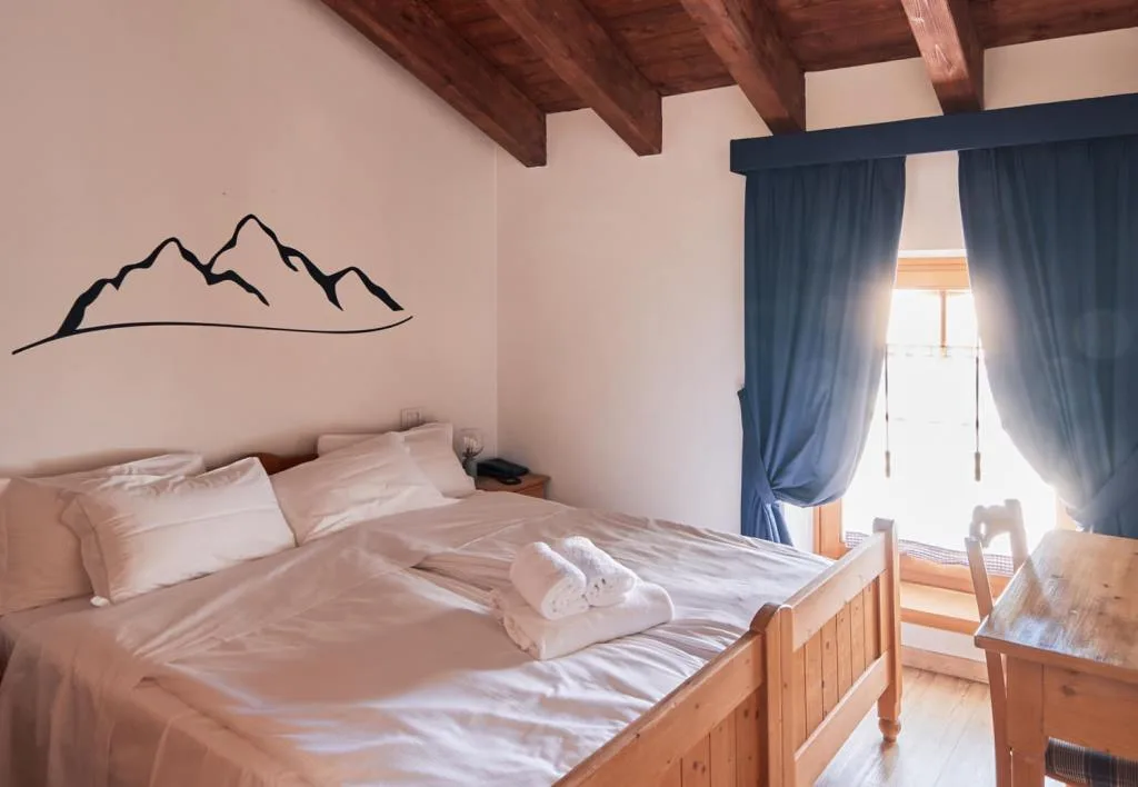 Camera matrimoniale con decorazione a montagne e tende blu alla finestra