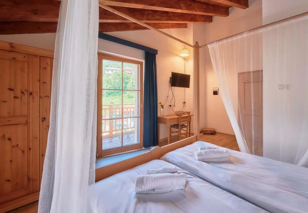 Camera con letto a baldacchino, scrivania, TV e accesso al balcone