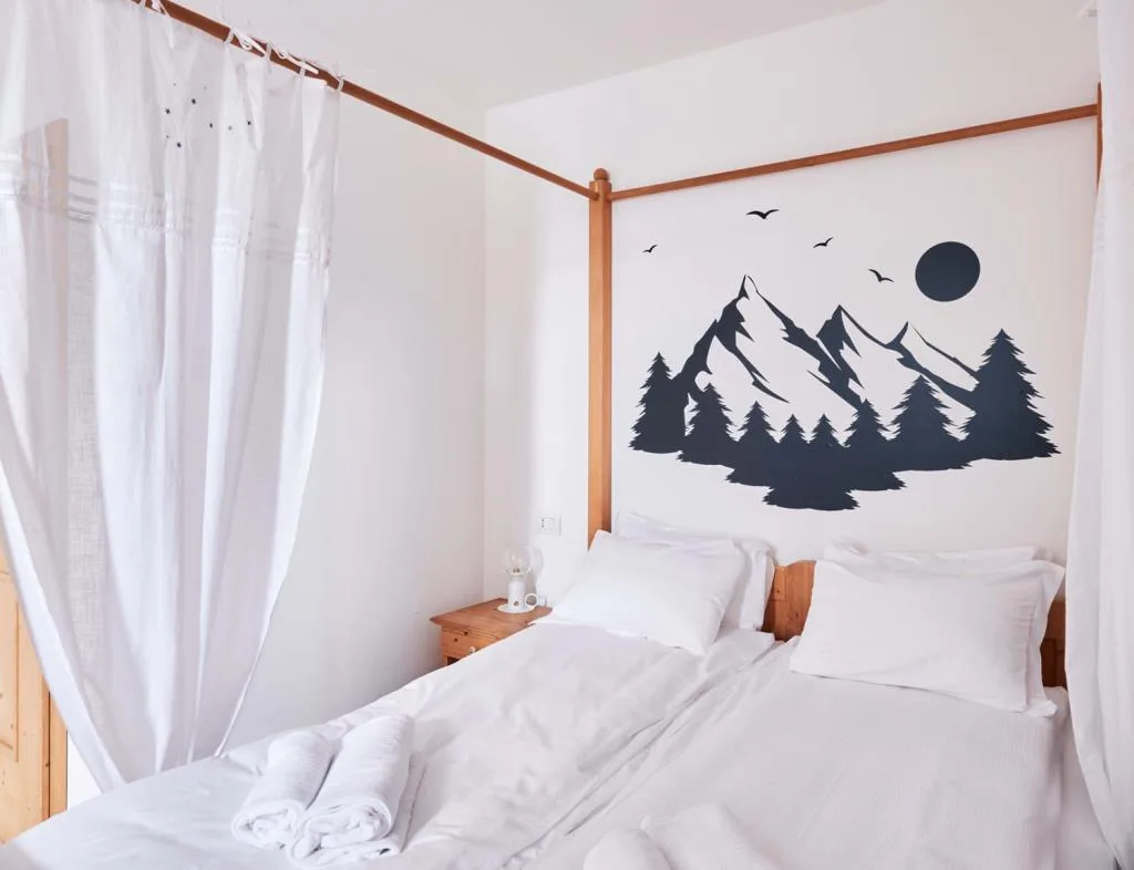 Camera con letto a baldacchino e murale di montagne, alberi e luna