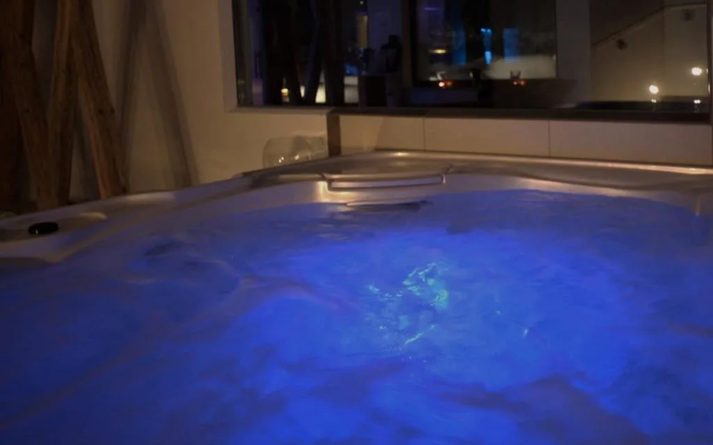 Vasca idromassaggio con acqua illuminata di blu e vista notturna dalla finestra