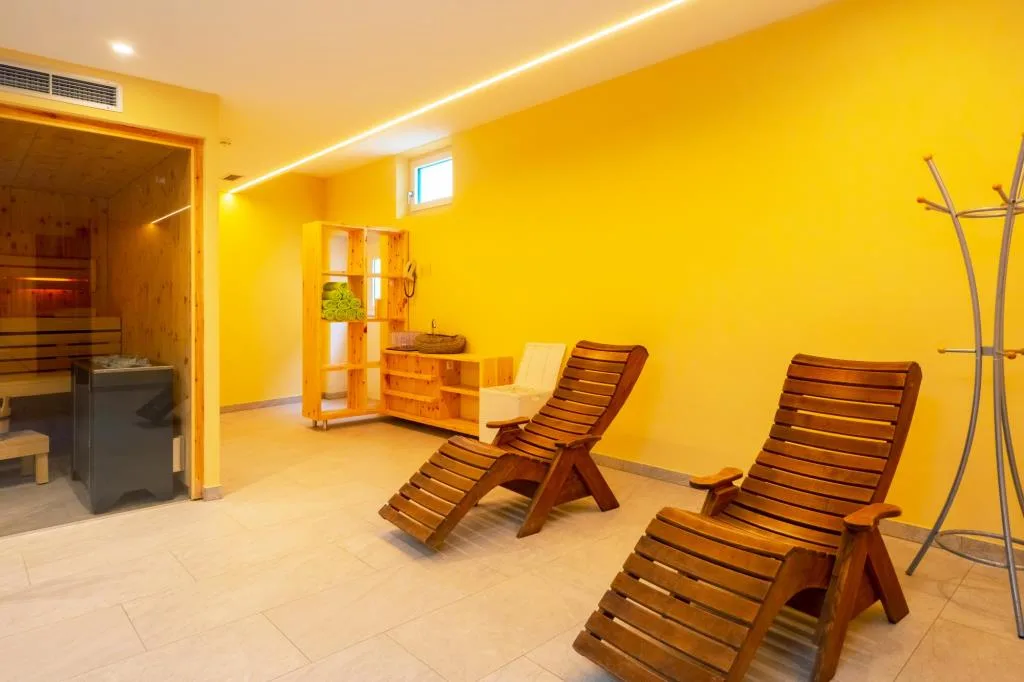 Area relax della sauna con lettini in legno e ingresso alla sauna finlandese