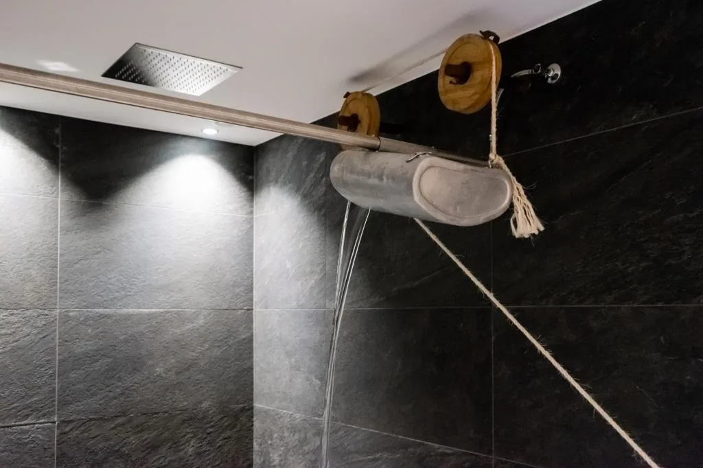Doccia emozionale con getto d'acqua a secchio e rivestimento in pietra nera