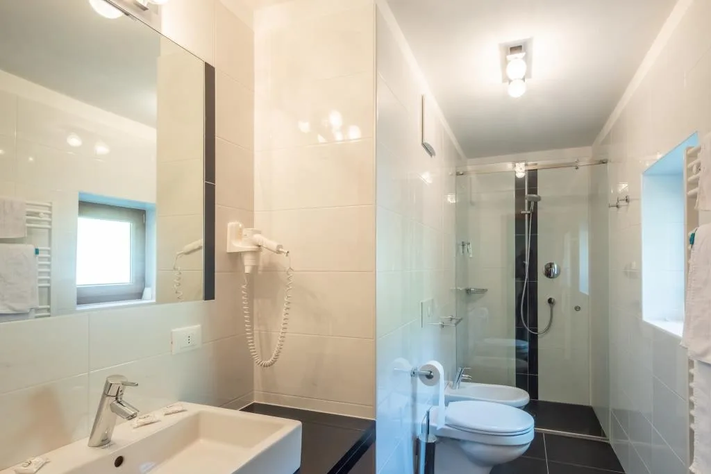 Bagno luminoso con doccia in vetro, lavabo, wc e bidet