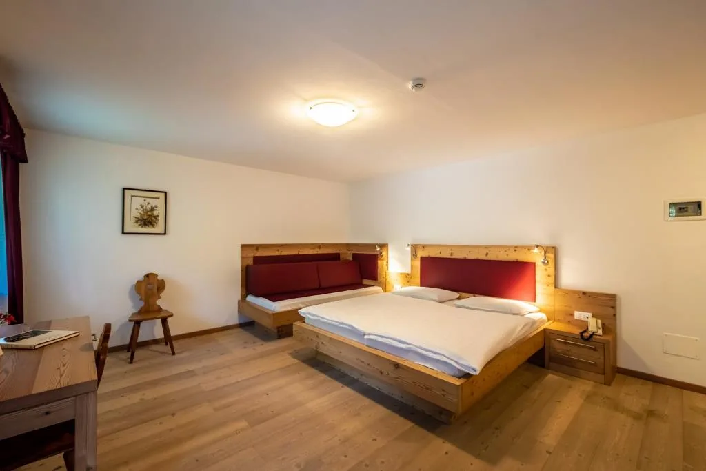 Camera in legno chiaro con letto matrimoniale e divano letto aggiuntivo