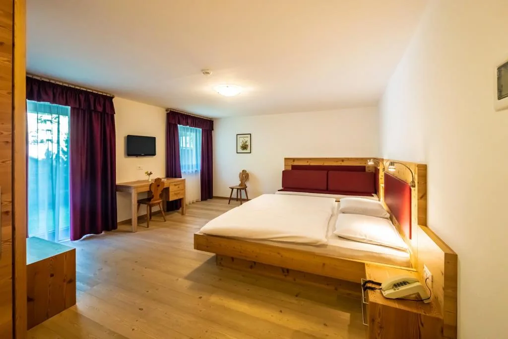 Ampia camera in legno con letto matrimoniale, scrivania e balcone